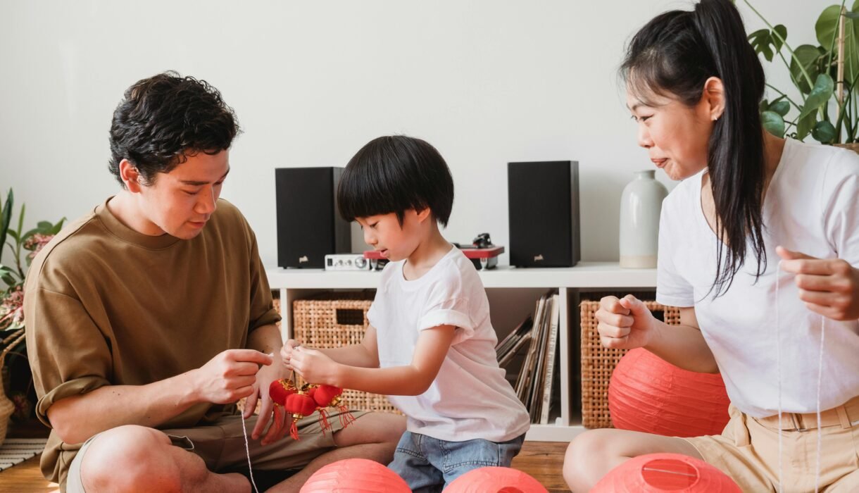 A family bonding with red lanterns indoors, capturing Asian cultural traditions.