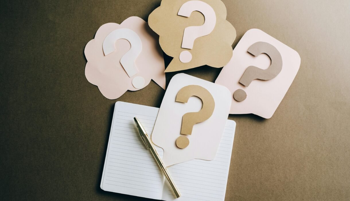 Flat lay of question mark paper crafts on a notebook, symbolizing questions and ideas.