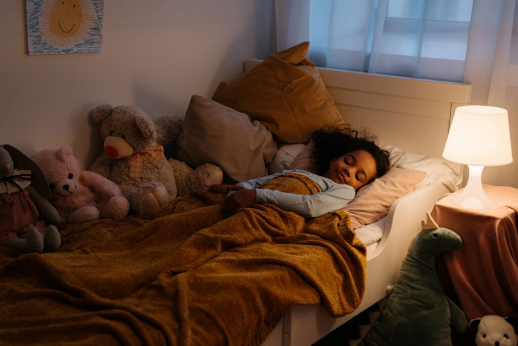 Smiling child peacefully asleep in bed with a soft blanket, showing the importance of quality sleep for children's health and development. smartkidsguide.com